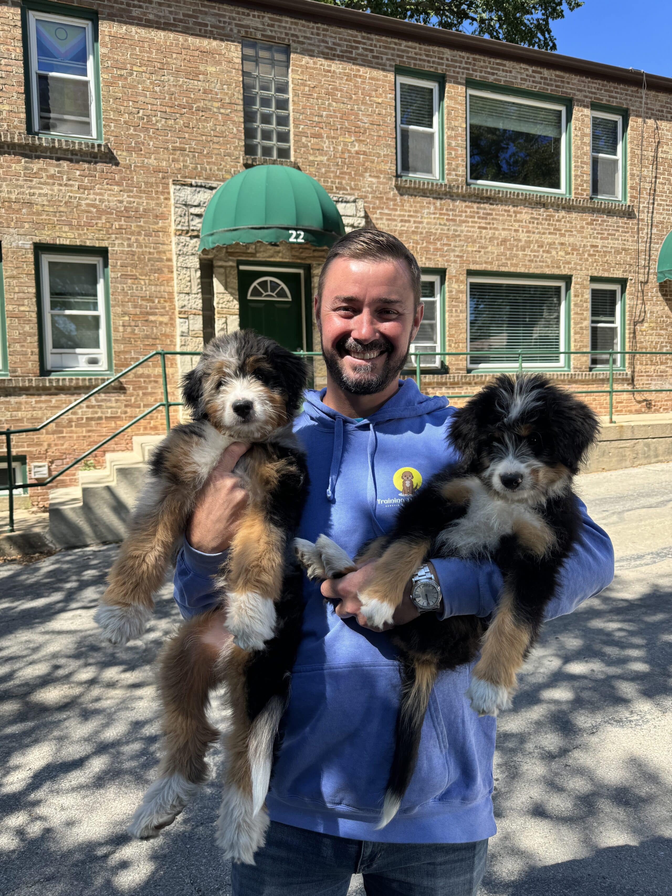 Tyler Morrick of Training That Lasts Holding 2 Mini Bernedoodles on their last day of their 3 week board and train